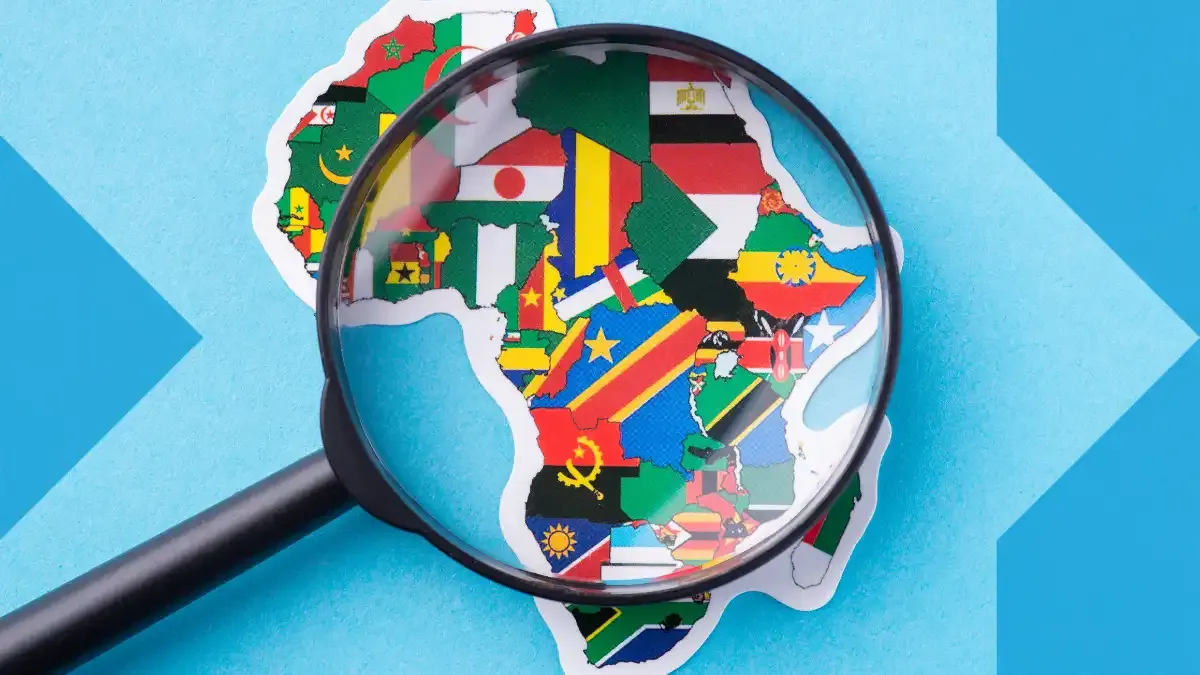 Mapa de África com bandeiras nacionais sob uma lupa, simbolizando o Dia da África, a herança cultural, a diáspora e o apoio familiar com sendvalu.
