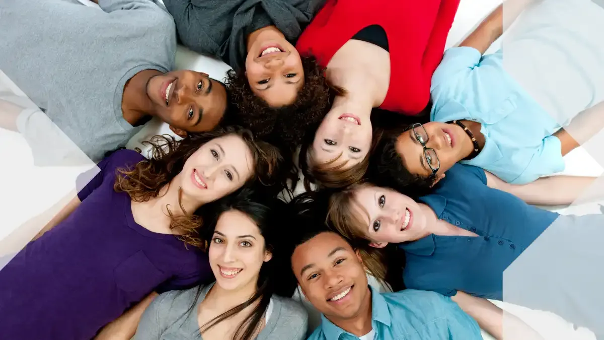 Grupo diverso de jóvenes adultos sonriendo juntos, representando a la juventud, la conexión, la inclusión y las aspiraciones compartidas en el Día Internacional de la Juventud.